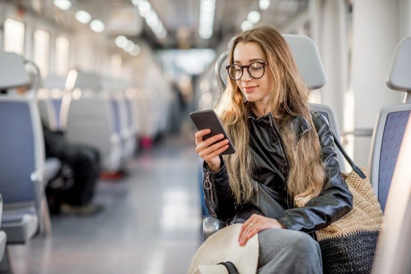 Woman Browsing Websites on her Cell Phone while Traveling